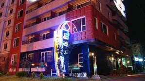 A multi-story hotel with a prominent neon sign, balconies, and a well-lit entrance. - Drama Motel (Boryeong)