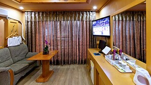 A hotel room with a sofa, a wooden table, a desk with toiletries, a television, and curtains. - Drama Motel (Boryeong)