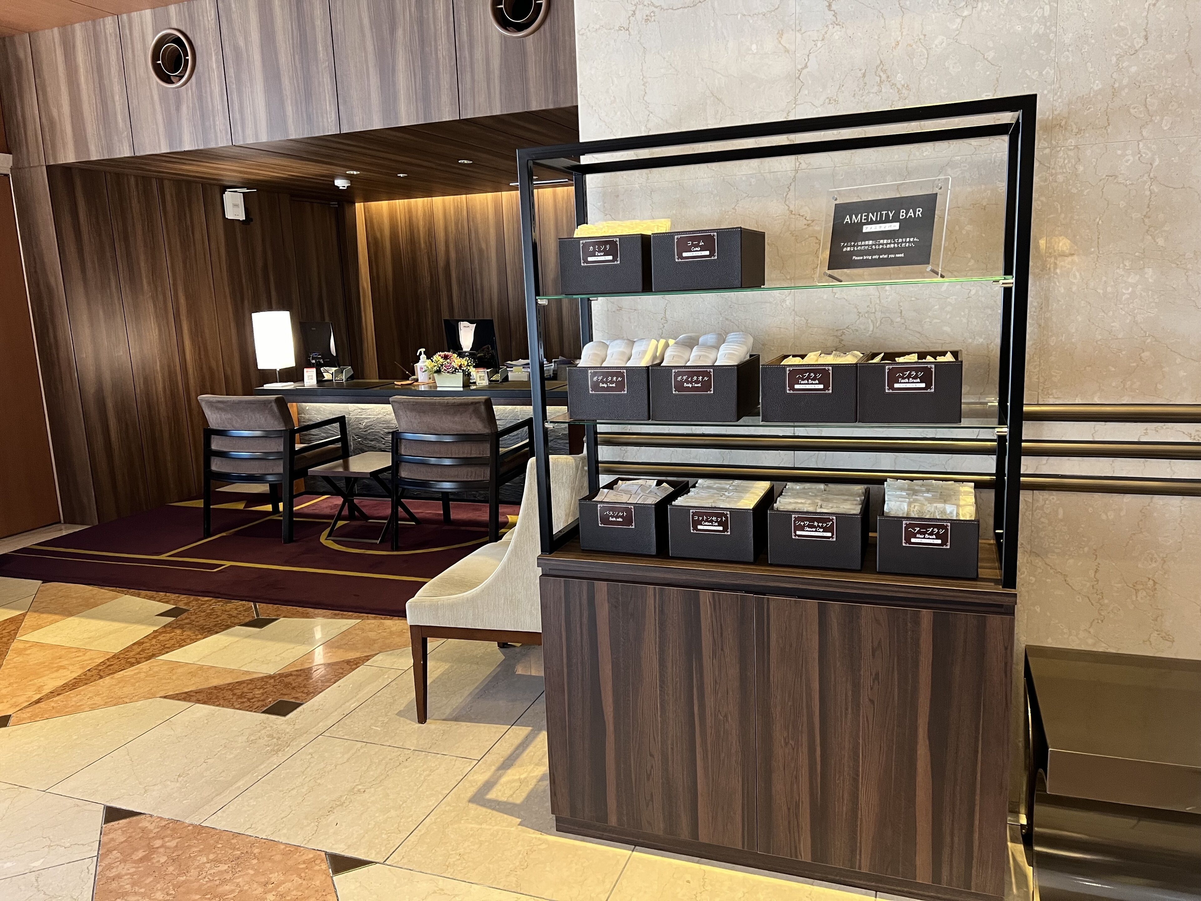 A hotel lobby with a reception desk, a seating area with chairs, and a display of toiletries.