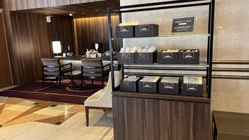 A hotel lobby with a reception desk, a seating area with chairs, and a display of toiletries.