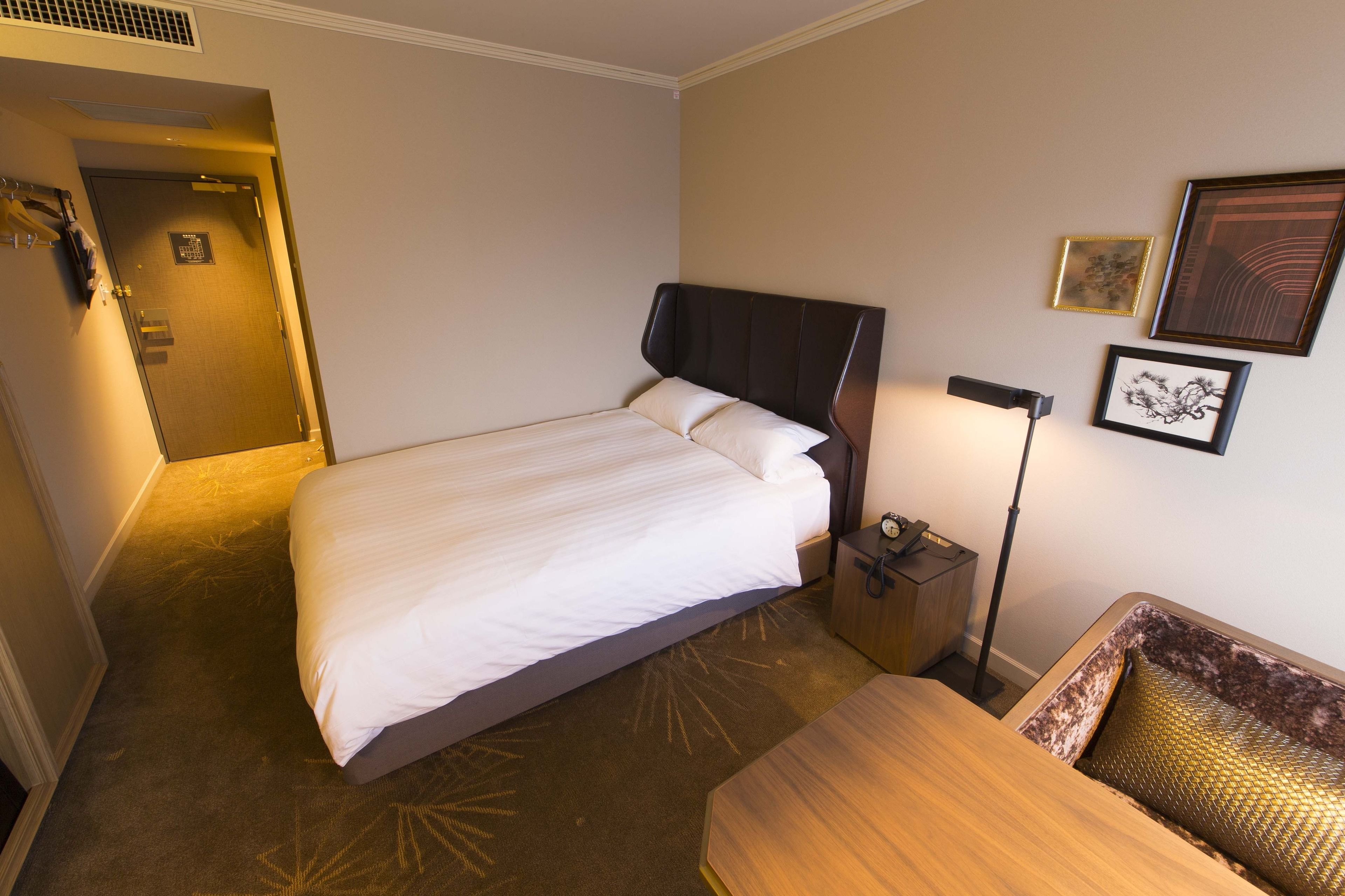 Una habitación de hotel con cama, mesita de noche, lámpara y decoración en la pared.