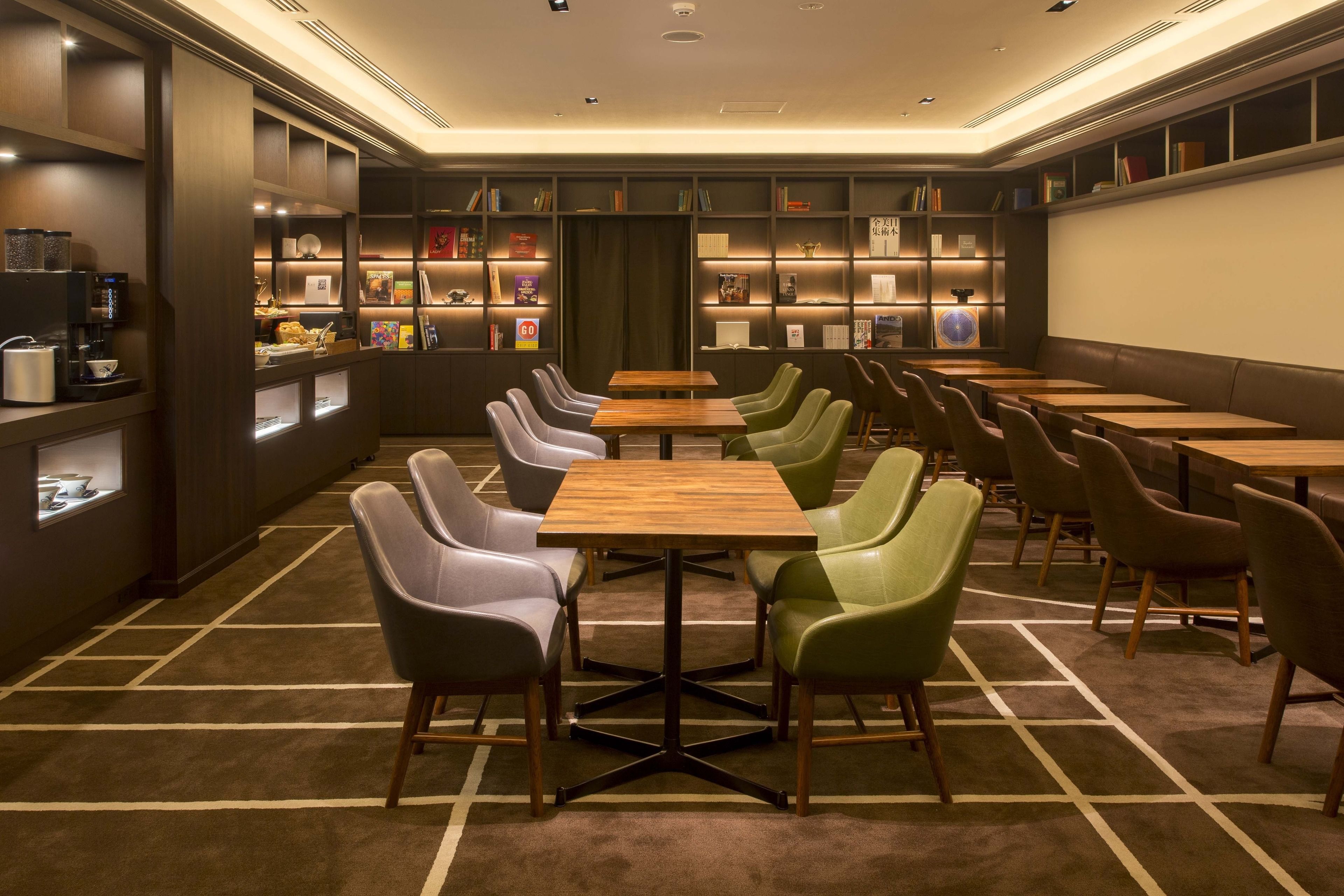 Una biblioteca moderna con filas de mesas y sillas, estanterías y una estación de café.