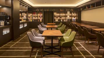 Una biblioteca moderna con filas de mesas y sillas, estanterías y una estación de café.