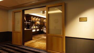 Un vestíbulo de hotel con una zona de recepción, una puerta de madera y suelo alfombrado.