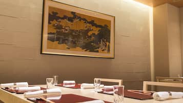 Una mesa de comedor elegantemente dispuesta con una obra de arte enmarcada encima, pared de madera y un interior moderno y limpio.