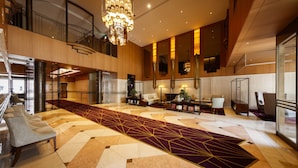 A spacious lobby with a geometric patterned carpet, a grand chandelier, and a modern staircase. - Royal Park Hotel Takamatsu (Takamatsu)