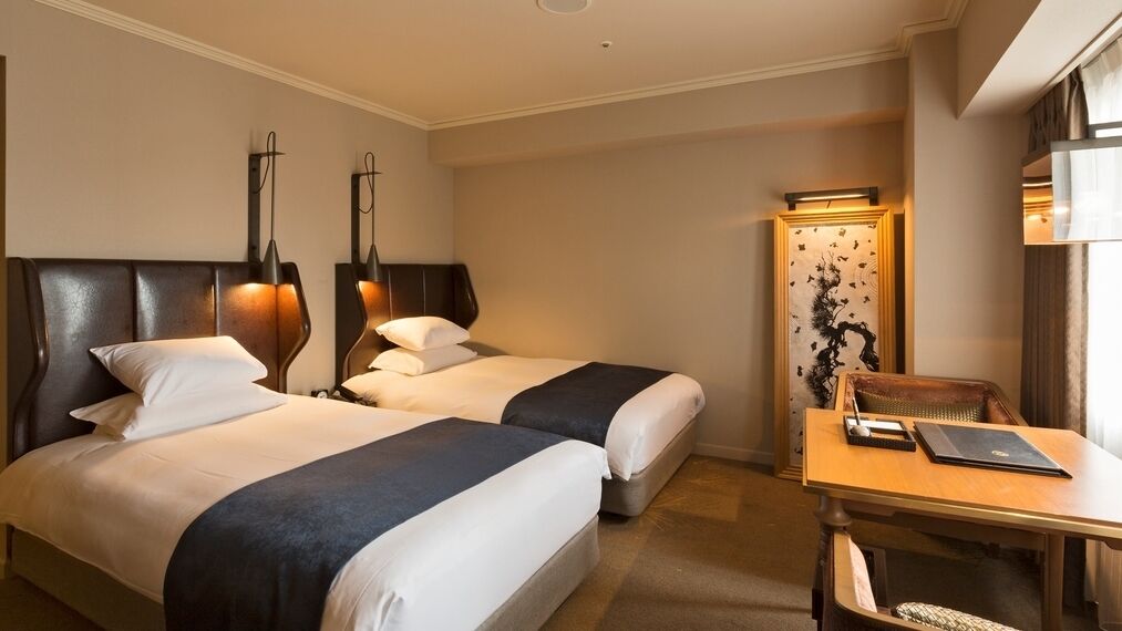 Ein Hotelzimmer mit zwei Betten, einem Schreibtisch und einem Stuhl.