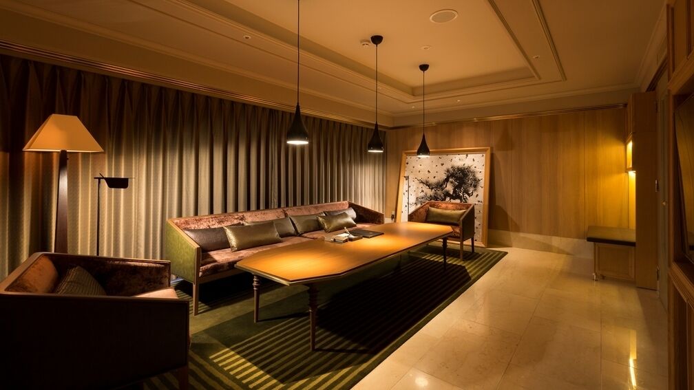 Ein modernes Hotelzimmer mit einer Couch, einem Couchtisch, einer Lampe und einem Gemälde an der Wand.