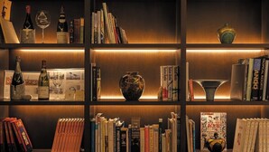 A bookshelf with books, wine bottles, and decorative items. - Royal Park Hotel Takamatsu (Takamatsu)