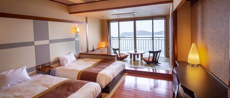 Une chambre d’hôtel avec deux lits, un bureau, une chaise et une vue sur la mer.