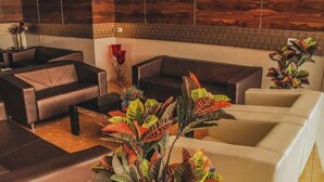 Un espace de détente moderne, avec des canapés et une table basse, entouré de plantes tropicales.