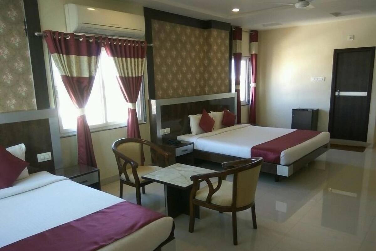 A hotel room with two beds, a desk, a chair, and a television.