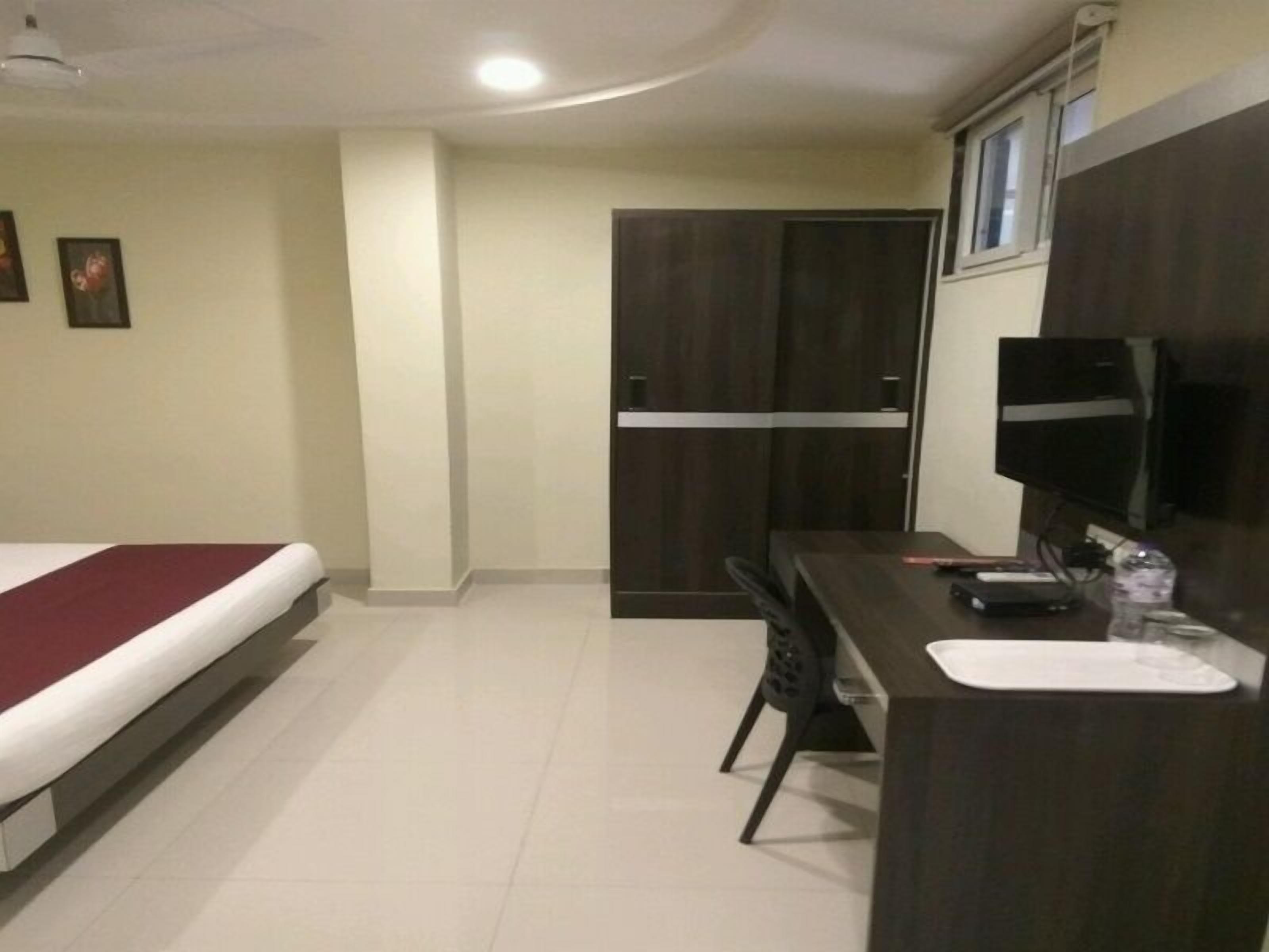 Een hotelkamer met een bed, een bureau, een stoel, een televisie en een kledingkast.
