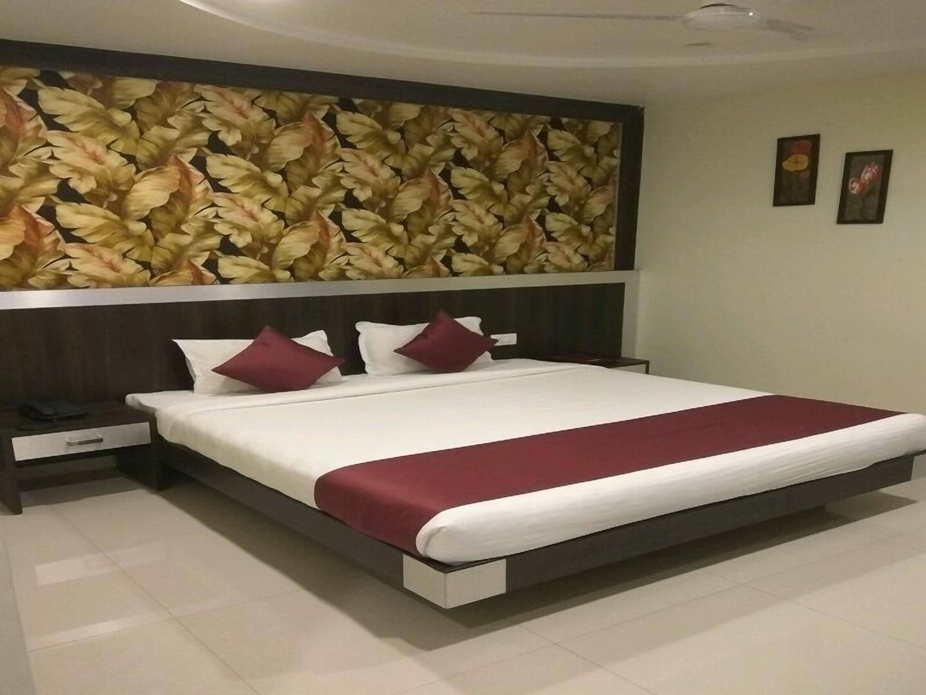 Une chambre d’hôtel moderne avec un grand lit, une table de chevet et un panneau décoratif mural.