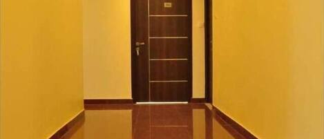 Un pasillo con puerta de madera y paredes amarillas.