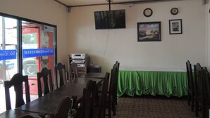 A conference room with a long table, chairs, a television mounted on the wall, and a clock.