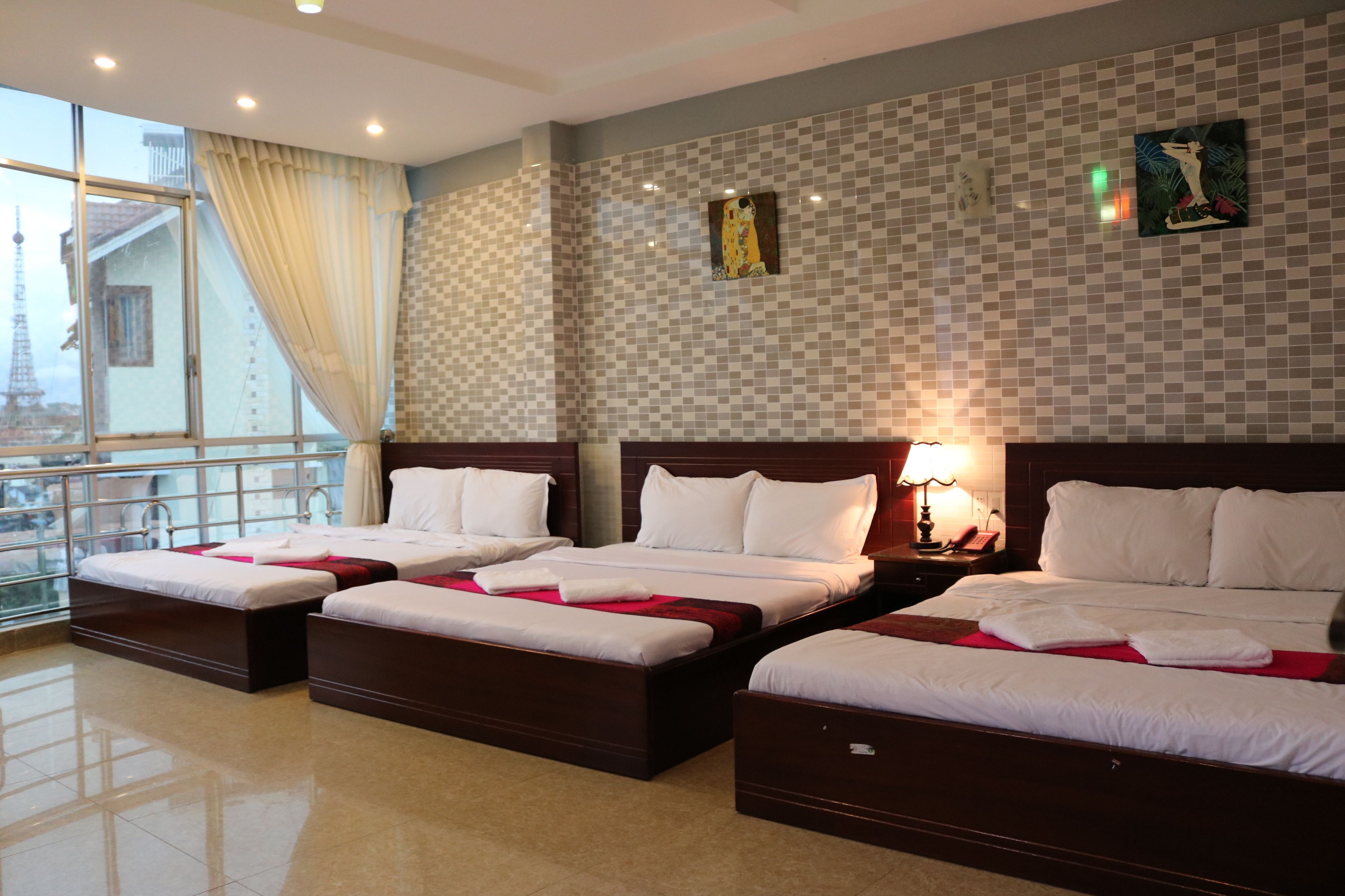 A hotel room with three beds, a large window, and a view of a tower.