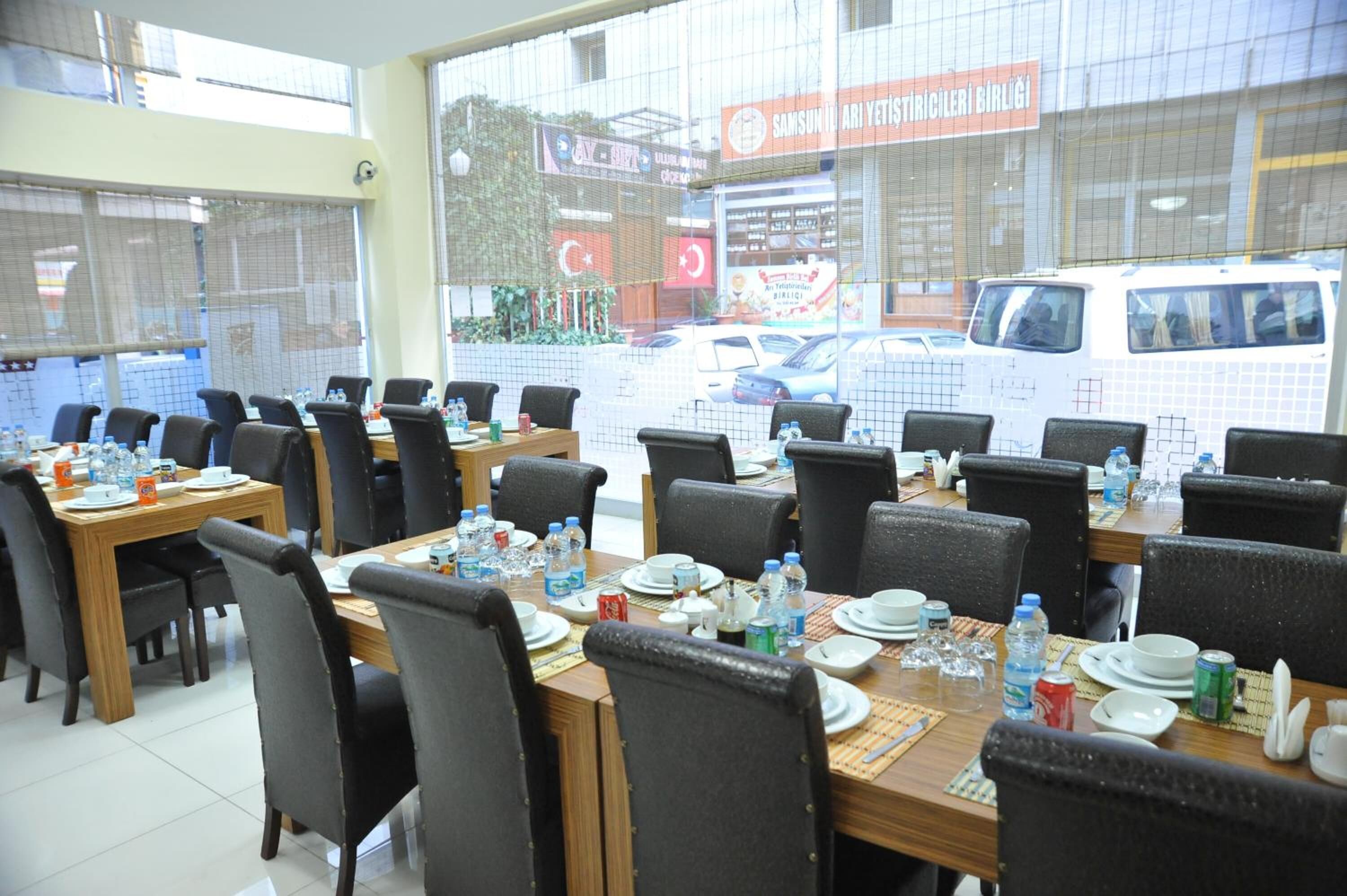 Un comedor con varias mesas dispuestas para comer, sillas y diferentes utensilios de mesa.