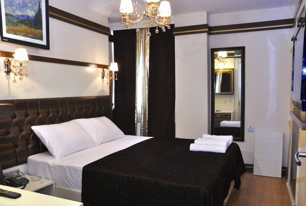 Habitación de hotel con una cama grande, una mesita de noche con teléfono, un espejo y un televisor.