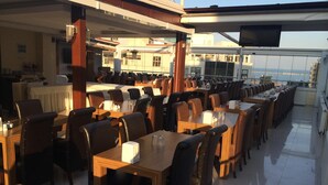 Un restaurante con varias mesas y sillas, un televisor montado en el techo y vistas de la ciudad.