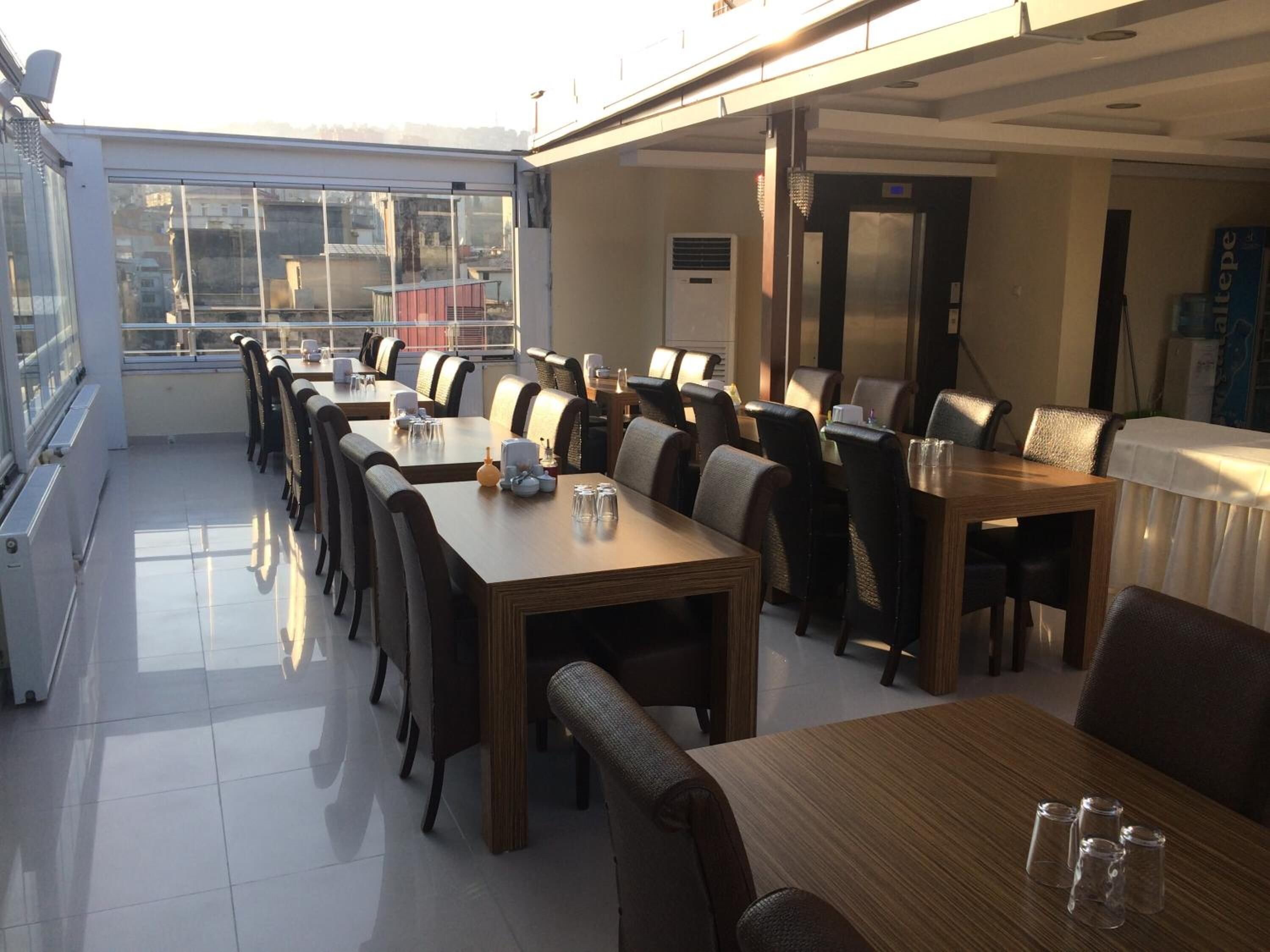 Un restaurant doté de nombreuses tables et chaises, de grandes fenêtres et d’un ascenseur.