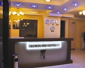 Una recepción con un cartel que dice "GLORIA TIBI HOTEL".