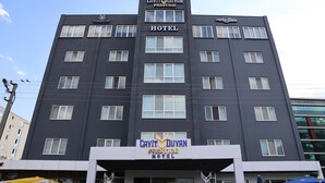Un edificio de hotel con varios pisos, grandes ventanales y un letrero llamativo que dice "Cavit Duyan Prestige Hotel".