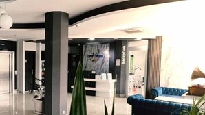 Un área de recepción moderna con un mostrador, un sofá azul y una planta grande en maceta.