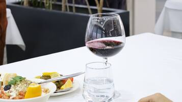 A dining table with plates of food, a glass of red wine, and a water glass.