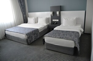 Una habitación de hotel con dos camas, una mesita de noche, un espejo y un suelo estampado.