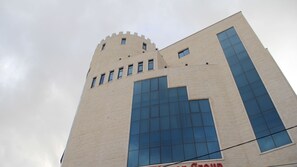 Ein hohes Gebäude mit einem markanten architektonischen Design, das große Fenster und eine schlanke, turmartige Struktur an der Spitze aufweist.