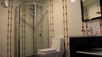 A bathroom with a glass-enclosed shower, a white toilet, and a black sink.