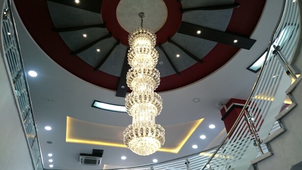 A modern interior with a central chandelier, a circular ceiling design, and a staircase. - Abu Mazen Hotel (Hebron)