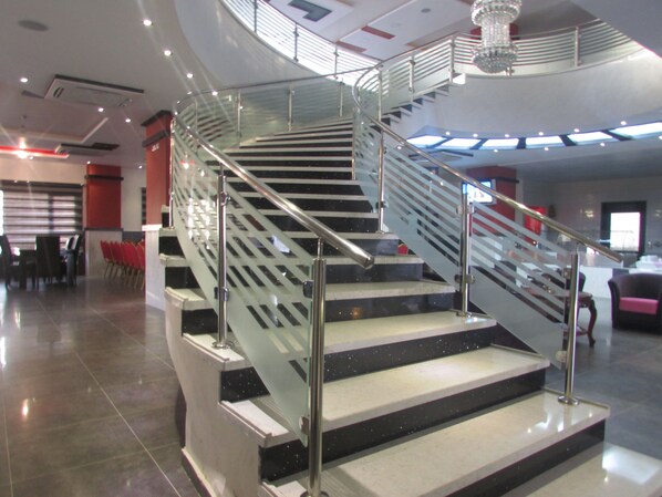 Ein modernes Interieur mit einer Glas- und Metalltreppe, die zu einer zweiten Etage führt.