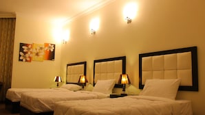 A hotel room with two beds, each with a headboard, bedside lamps, and a painting on the wall. - Abu Mazen Hotel (Hebron)