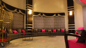 A modern living room with a curved sofa, two coffee tables, and a red chair. - Abu Mazen Hotel (Hebron)