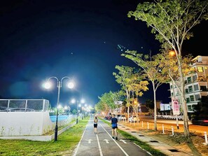 A nighttime street with a pedestrian path, streetlights, trees, and buildings. -  Santorini Hotel (Miri)