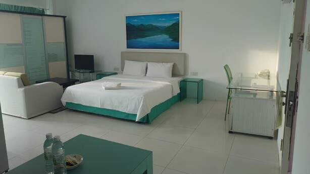 Una habitación de hotel con una cama, un escritorio con una silla, un televisor y un cuadro en la pared.
