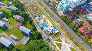 Vista aérea de uma paisagem urbana com um grande mural em um edifício, ruas e edifícios ao redor.
