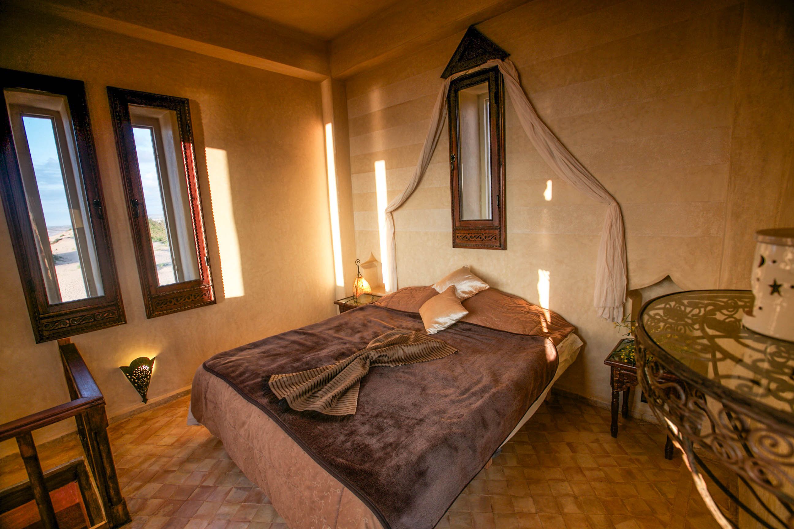 Una camera da letto con un letto grande, un baldacchino, due comodini e un tavolino con piano in vetro.
