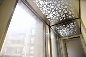 A window with a patterned screen and a view of a building outside. - San Marciano (Syracuse)