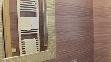 A bathroom with a sink, mirror, towel rack, and a small round table with a pair of shoes.