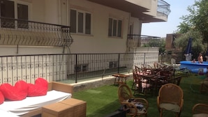 A balcony with wicker furniture, a pool, and a covered area with chairs. - Öz Mert Hotel (Konyaalti)