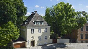 A two-story building with a gabled roof, a small porch, and a garage. - Residenz am englischen Garten (Munich)