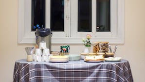 Una mesa dispuesta con platos, tazas y un florero frente a una ventana con marco blanco.