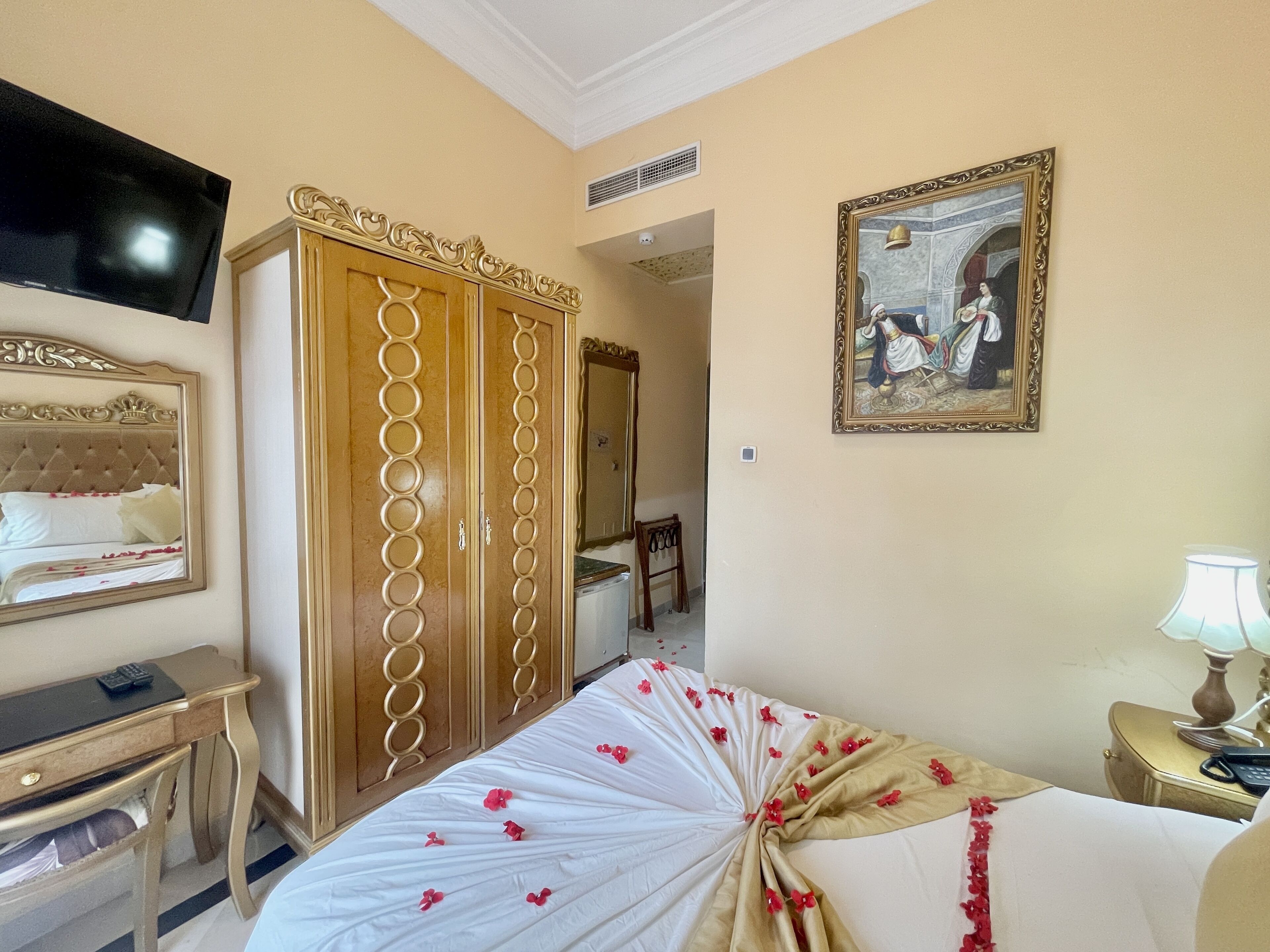 Ein Hotelzimmer mit Bett, Schreibtisch, Kleiderschrank, Fernseher und einem Bild an der Wand.