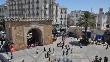 A public square with a large stone archway, surrounded by buildings and a busy street.