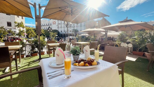 An outdoor dining area with tables, umbrellas, and a view of a historic building. - Royal Victoria - Ex British Embassy (Tunis)