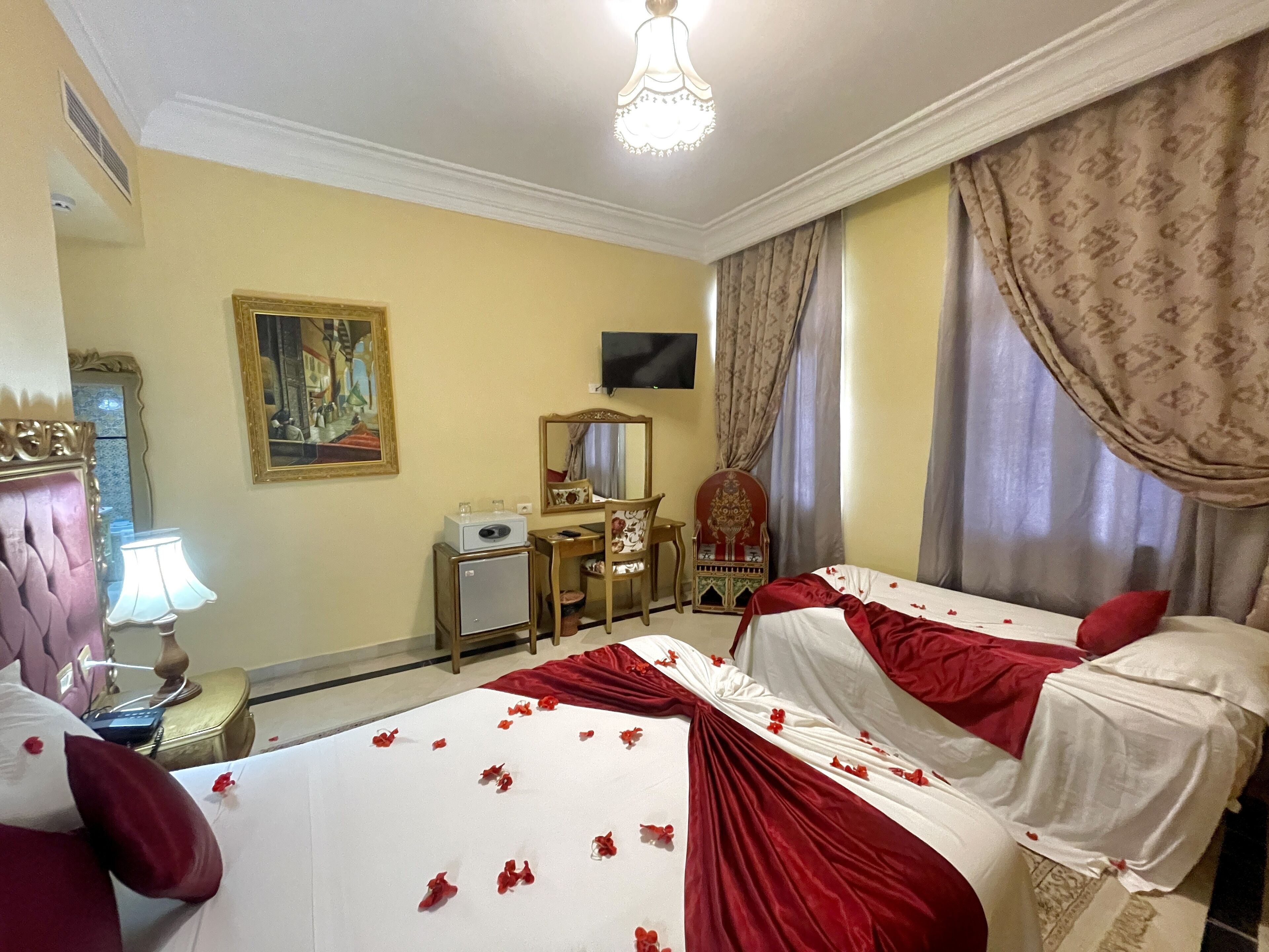 Habitación de hotel con cama, escritorio, silla, televisión y un cuadro en la pared.