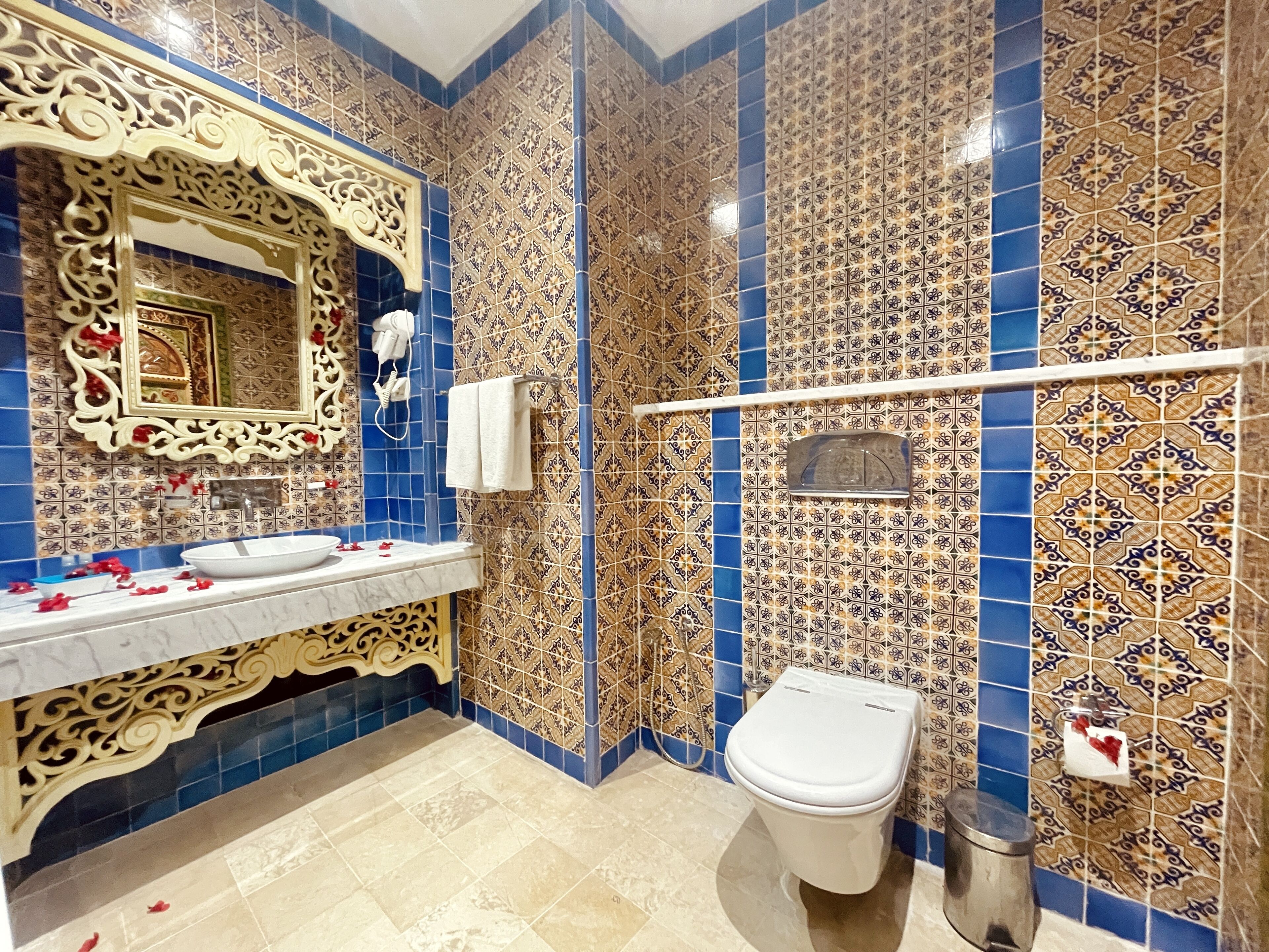 Un baño con lavamanos, espejo, inodoro y azulejos decorativos.
